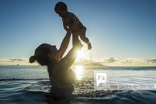 Mutter spielt mit ihrem kleinen Baby im Wasser bei Sonnenuntergang  Papeete  Tahiti