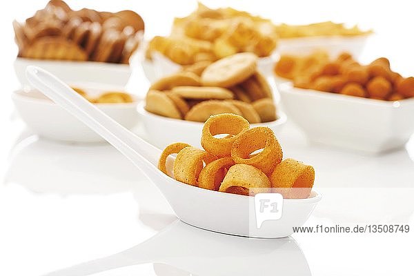 Potatoe rings on spoon with a variety of spicy snacks
