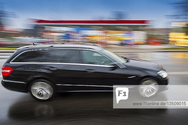 Schwarzer PKW in schneller Fahrt vor Tankstelle Bewegungsunschärfe Deutschland Europa