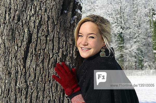 Young woman leaning against a tree in winter