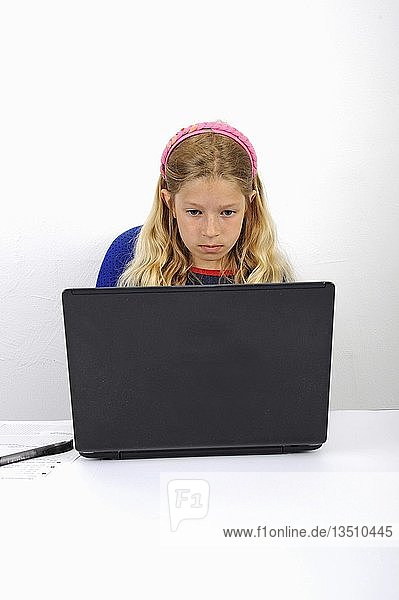 Junge Schülerin macht ihre Hausaufgaben mit einem Laptop