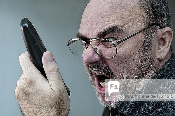 Wütender Mann  der in einen Telefonhörer schreit