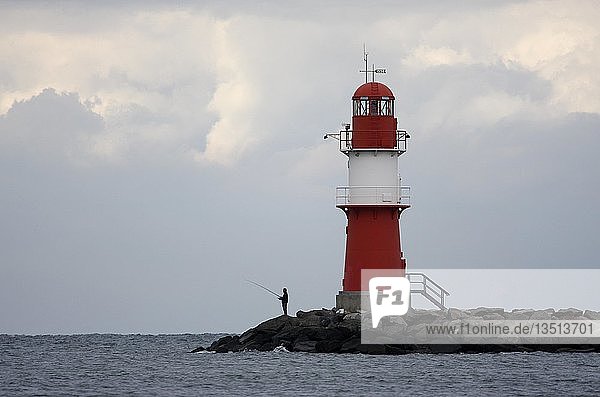 Mann beim Angeln an einem Leuchtturm an der Ostseeküste  Warnemünde  Mecklenburg-Vorpommern  Deutschland  Europa