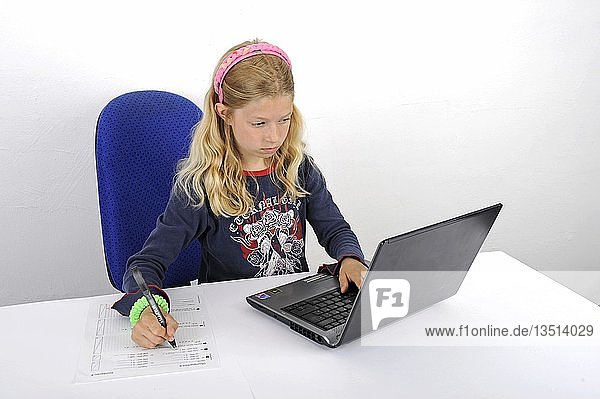 Junge Schülerin macht ihre Hausaufgaben mit einem Laptop