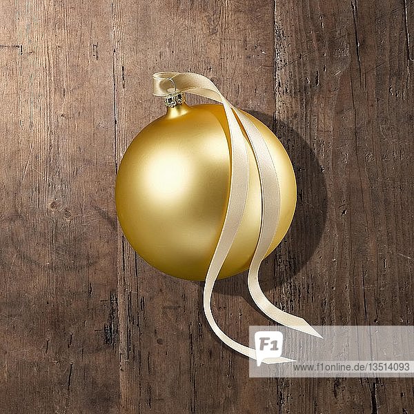 Eine goldene Weihnachtskugel mit Schleife  auf Holzteller  Deutschland  Europa