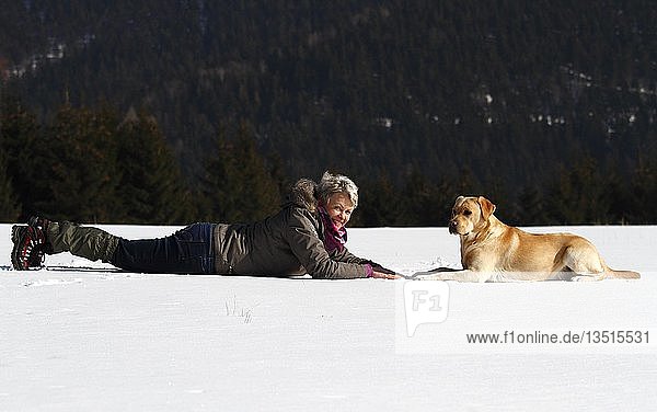 Frau mit Golden Retriever im Schnee liegend  Thüringen  Deutschland  Europa