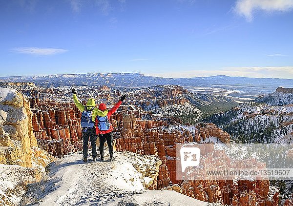 Touristen mit ausgestreckten Armen mit Blick auf das Amphitheater  bizarre schneebedeckte Felslandschaft mit Hoodoos im Winter  Rim Trail  Bryce Canyon National Park  Utah  USA  Nordamerika