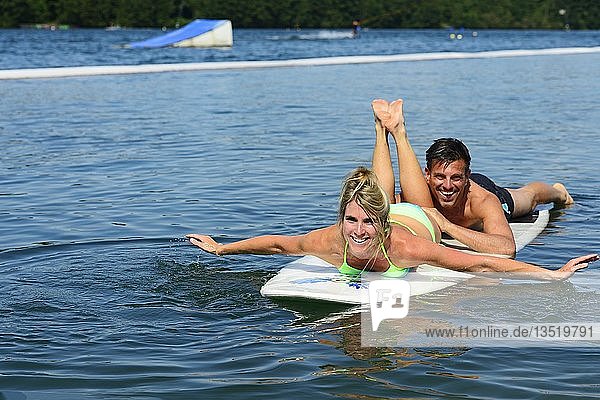 Couple on SUP board  Wake Lake  Woerth an der Isar  East Bavaria  Lower Bavaria  Bavaria  Germany  Europe
