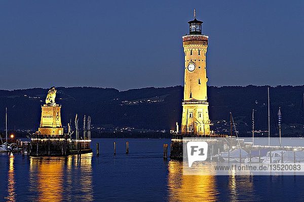 Beleuchteter bayerischer Löwe und der Leuchtturm in der Abenddämmerung  Lindau am Bodensee  Schwaben  Bayern  Deutschland  Europa