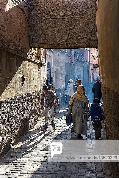 Locals in a narrow alley between houses  backlight  alleyway scene  Fez Medina  Fes  Morocco  Africa