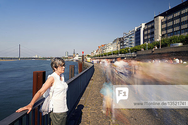 Woman standing at the rails on the banks of the river Rhine  Duesseldorf  North Rhine-Westphalia  Germany  Europe