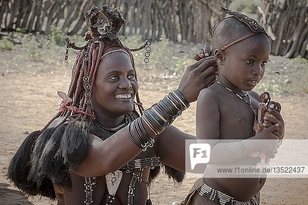 Ovahimba or Himba  a mother puts headdress on her son  Kunene district  Namibia  Africa