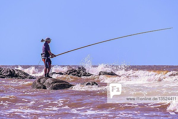 Angler in the surf of the Rio de la Plata beach Rambla Montevideo Uruguay South America