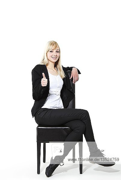Junge Frau auf einem Stuhl sitzend  den Daumen nach oben zeigend