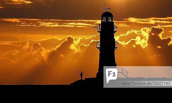 Angler beim Angeln im Sonnenuntergang neben einem Leuchtturm  Ostsee  Warnemünde  Deutschland  Europa