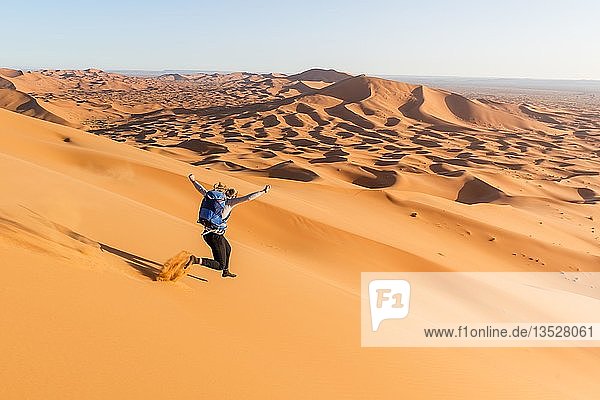 Frau läuft bergab  rote Sanddünen in der Wüste  Dünenlandschaft Erg Chebbi  Merzouga  Sahara  Marokko  Afrika