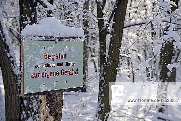 Verschneites Schild  das vor Schnee und Eis warnt