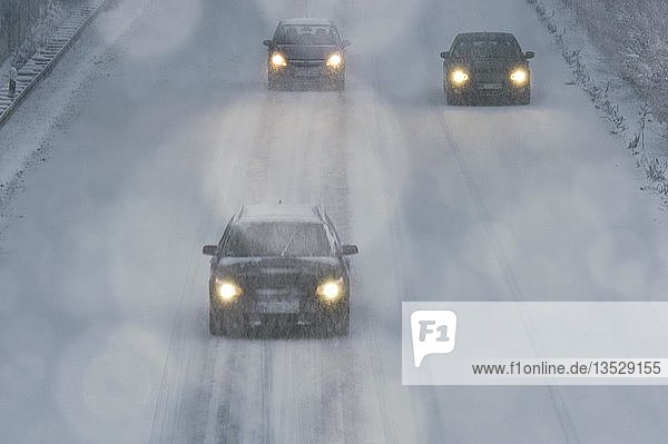 Drei Autos fahren im Schneegestöber auf einer Landstraße