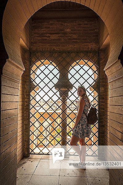 Frau steht am Fenster im Bogengang  Glockenturm La Giralda der Kathedrale von Sevilla  Catedral de Santa Maria de la Sede  Sevilla  Andalusien  Spanien  Europa