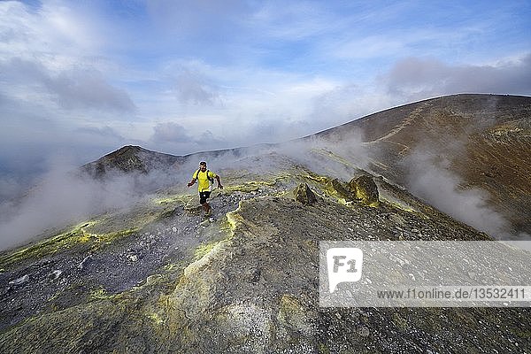 Trailrunner surrounded by sulfur fumaroles and chloride crusts on the crater rim  Gran Cratere  Vulcano Island  Aeolian and Lipari Islands  Sicily  Italy  Europe