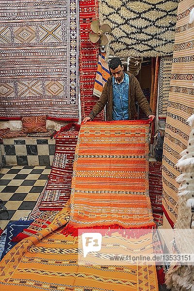 Carpet dealer shows a Moroccan carpet  Souk in the medina  Fes el Bali  Fez  Morocco  Africa