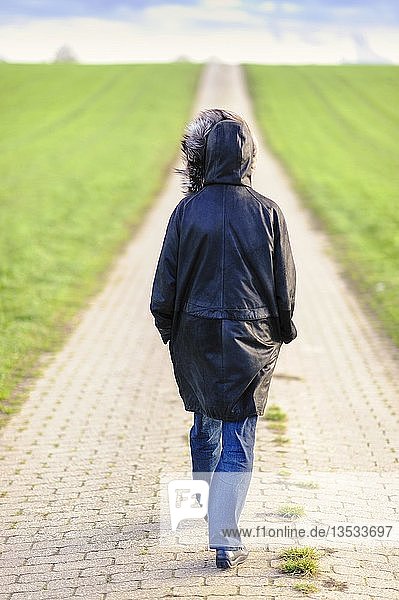 Frau geht auf einem Feldweg  von hinten  Grevenbroich  Nordrhein-Westfalen  Deutschland  Europa
