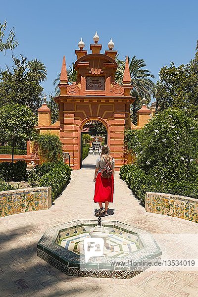 Junge Frau in rotem Kleid in den Gärten des Alcazar  Springbrunnen  Königspalast von Sevilla  Sevilla  Spanien  Europa