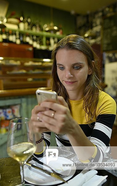 Junge Frau schaut auf ihr Mobiltelefon in einer Tapas-Bar  San Cristobal de La Laguna  Teneriffa  Kanarische Inseln  Spanien  Europa