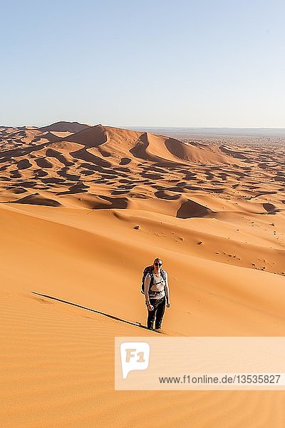 Frau steht im Sand auf Düne  rote Sanddünen in der Wüste  Dünenlandschaft Erg Chebbi  Merzouga  Sahara  Marokko  Afrika
