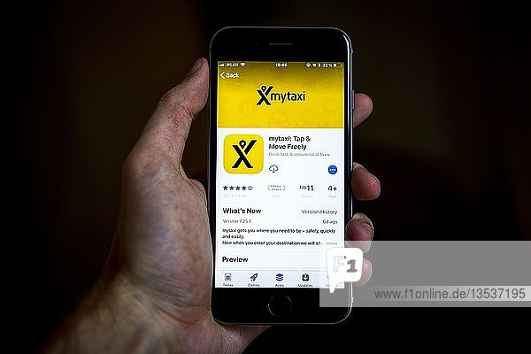 Hand  die ein iPhone hält  auf dem die mytaxi-App  eine App für Taxifahrer  im Apple App Store angezeigt wird  App-Symbol  Display  iPhone  iOS  Smartphone  Deutschland  Europa