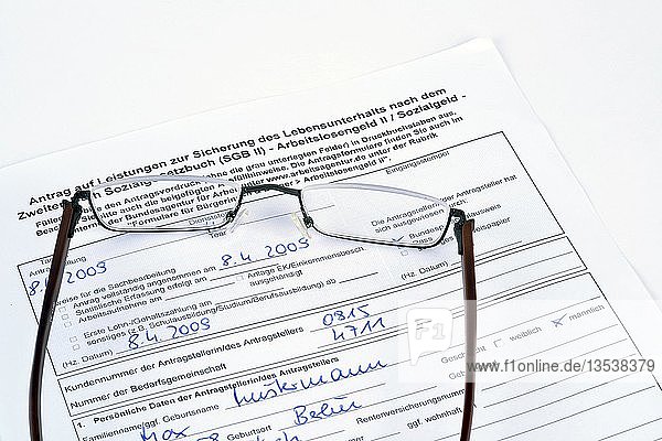 Reading glasses lying on a German application for an unemployment benefit  Hartz IV