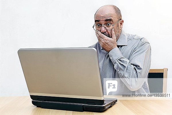 Mann schaut entgeistert auf den Bildschirm seines Laptops