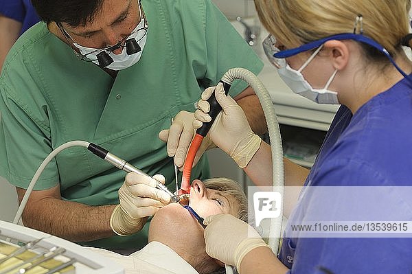 Zahnarzt und Assistentin mit einem Patienten während einer Zahnbehandlung
