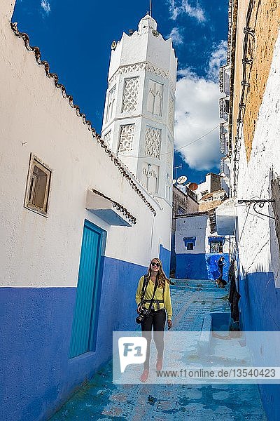 Young woman in the old town in front of a mosque  Blue house walls  Medina of Chefchaouen  Chaouen  Tangier-Tétouan  Kingdom of Morocco