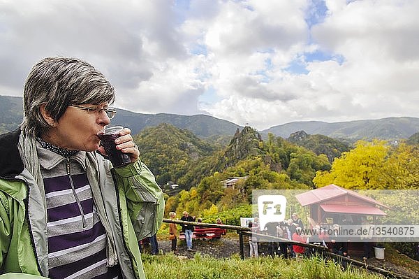 Eine Frau genießt eine Tasse Federroter  gärender neuer Rotwein  oberhalb des Rotweinwanderweges  Altenahr  Rheinland-Pfalz  Deutschland  Europa