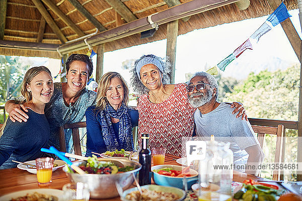 Portrait happy friends enjoying healthy meal in hut during yoga retreat