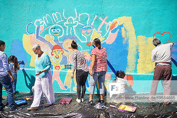Community volunteers painting vibrant mural on sunny wall