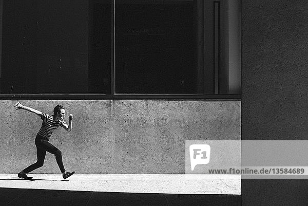 Young man walking on sunny urban sidewalk