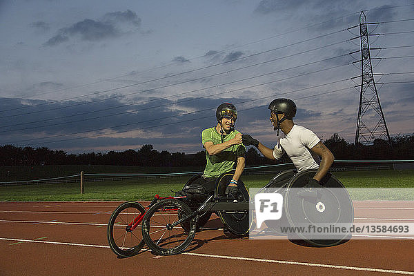 Querschnittsgelähmte Athleten stoßen sich auf der Sportbahn die Fäuste und trainieren nachts für ein Rollstuhlrennen