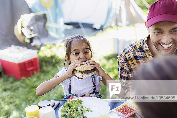 Vater und Tochter essen Grillhamburger auf dem Campingplatz