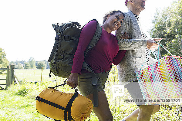 Affectionate couple carrying camping equipment