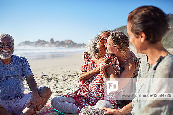 Happy women hugging on sunny beach during yoga retreat
