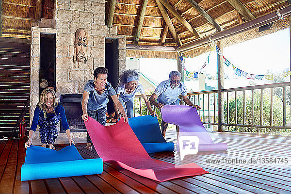 People unrolling yoga mats in hut during yoga retreat