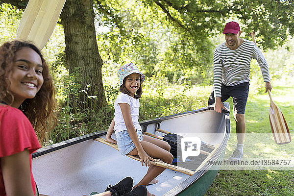 Family carrying canoe in woods