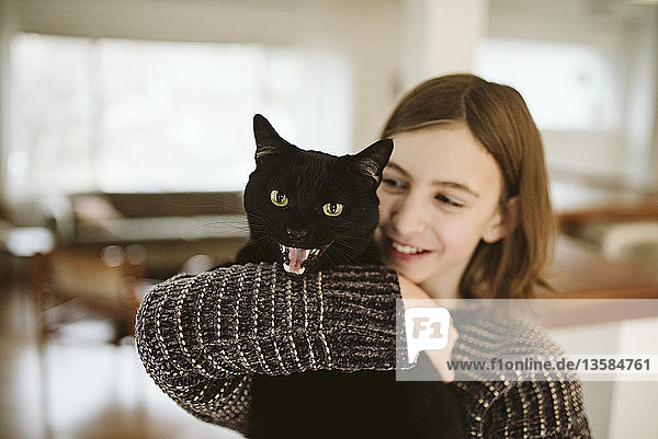Portrait girl holding hissing black cat