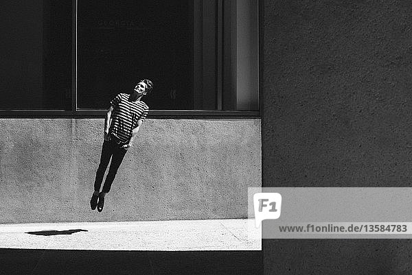Junger Mann springt auf städtischem Bürgersteig