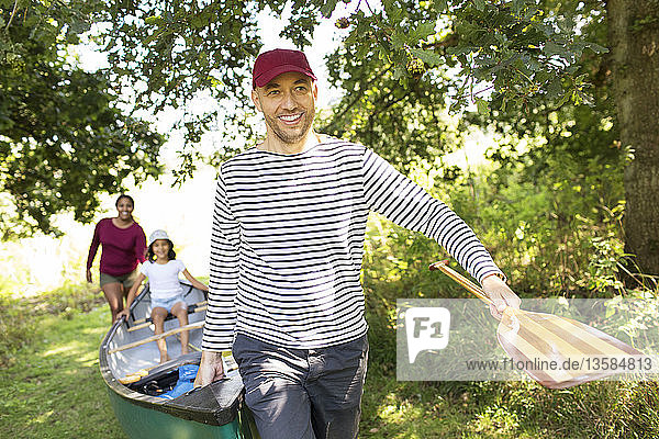 Family carrying canoe in woods
