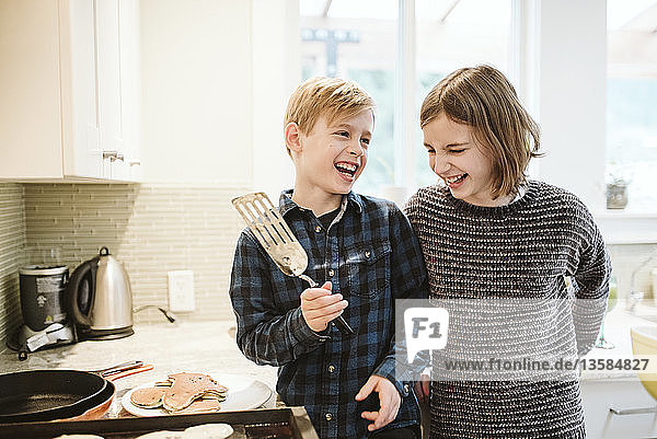 Glücklicher Bruder und Schwester machen Pfannkuchen in der Küche