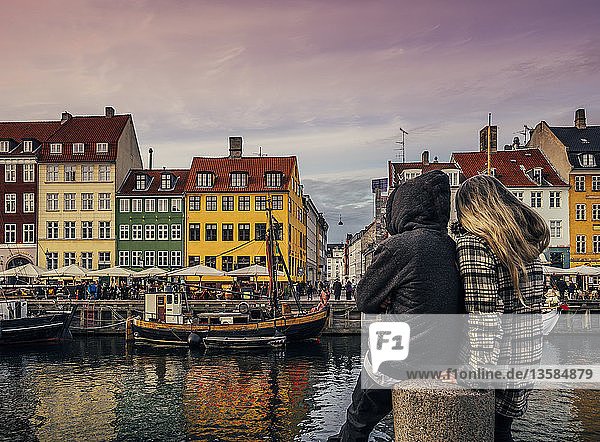 Paar genießt Blick auf Kanal und bunte Gebäude  Kopenhagen  Dänemark