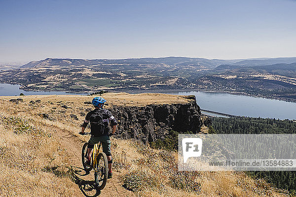 Mann fährt Mountainbike und genießt die Aussicht auf den Columbia River von einer Klippe aus  Hood River  Oregon  USA